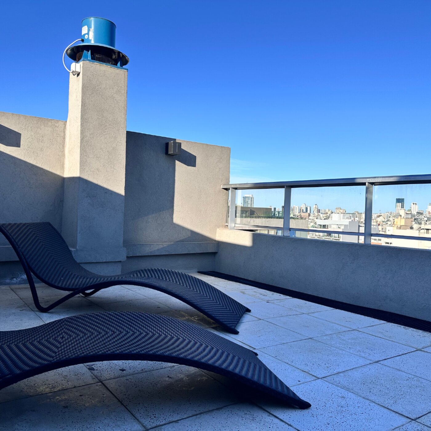 Terraza con reposeras y vista panorámica de la ciudad