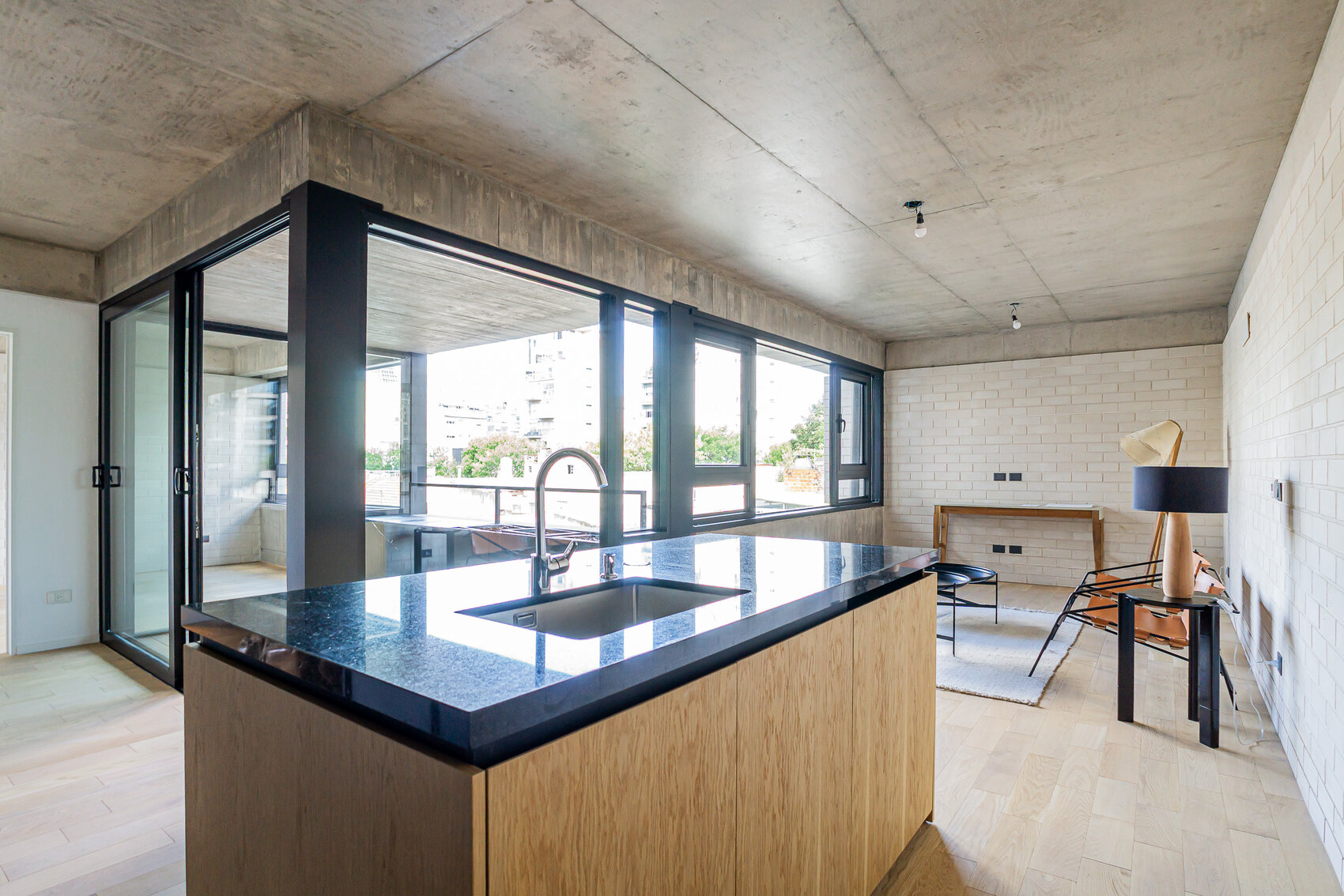 Cocina con isla y mesada negra junto al ventanal