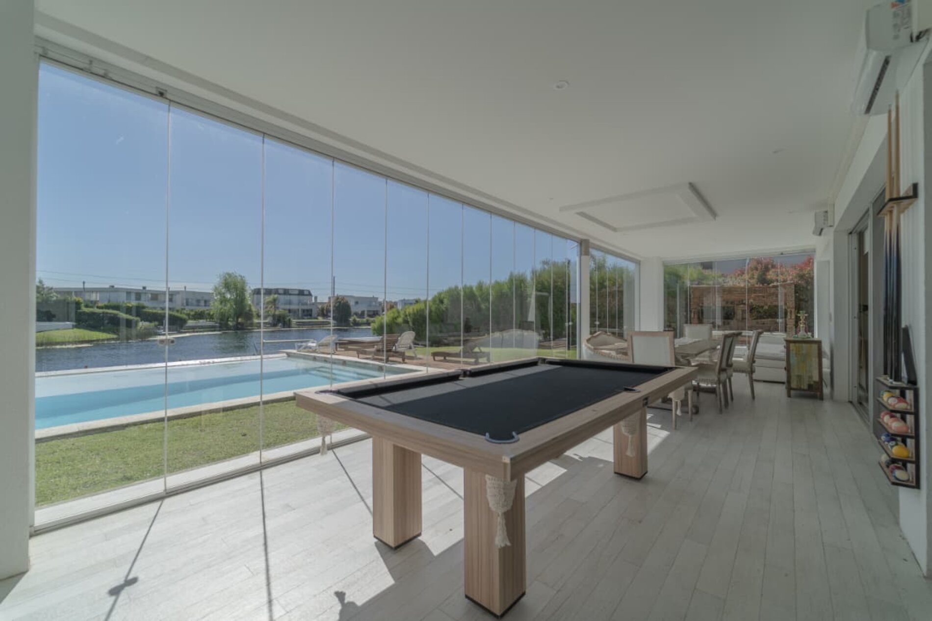 Living con mesa de pool y ventanal corrido con vista a la laguna