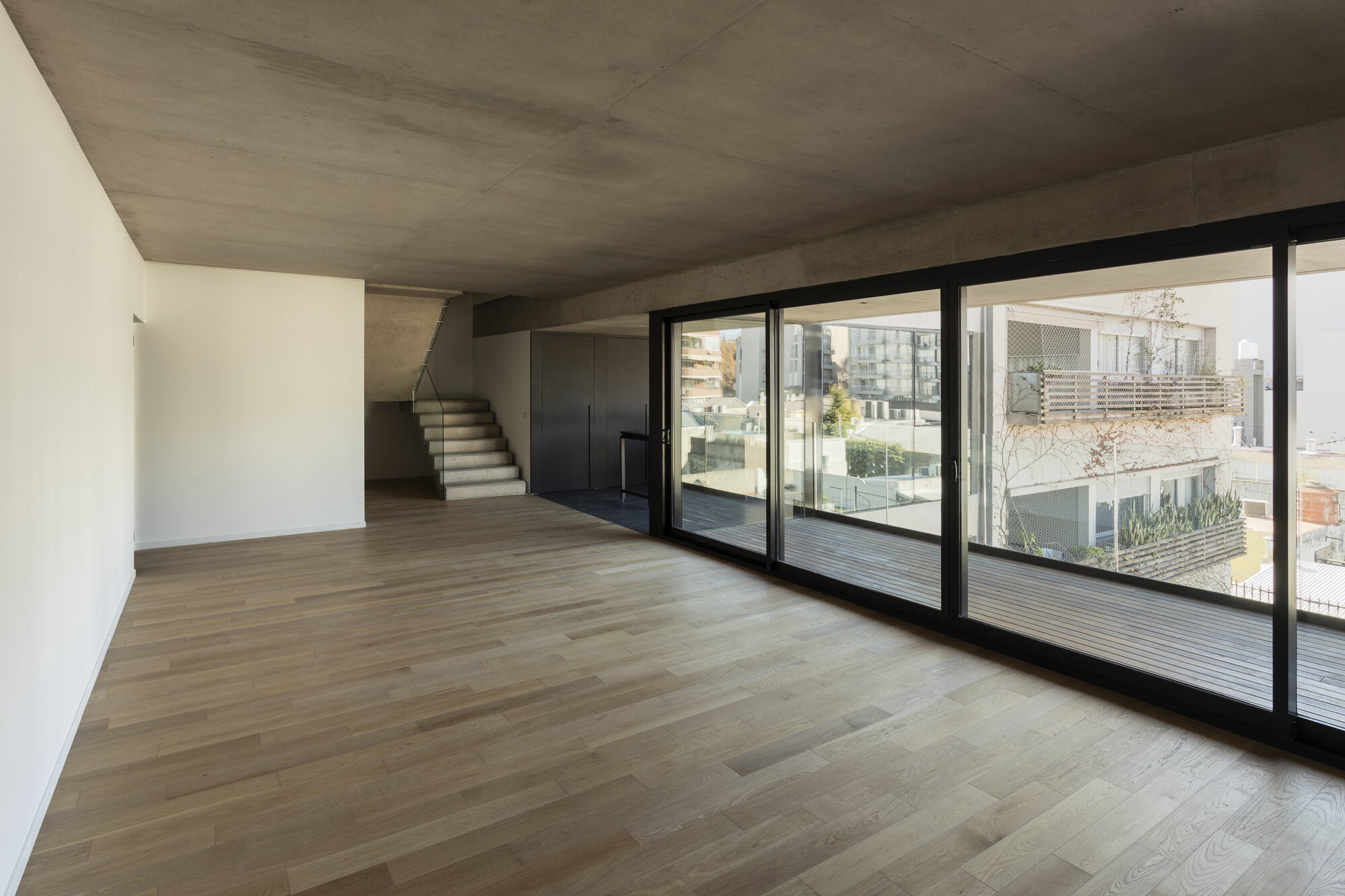 Ambiente amplio del dúplex con escalera interna y ventanales de piso a techo