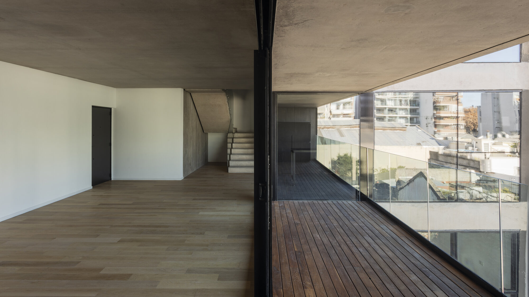 Escalera interna del dúplex con salida al balcón aterrazado con deck de madera